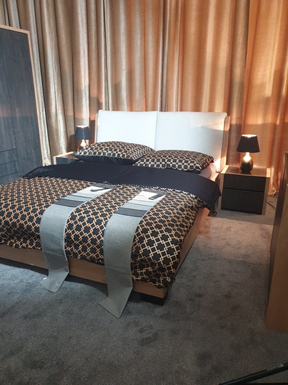 Łóżko Modello: Nowoczesne łóżko z drewna dąb Hikora i miękkim, poduchowym zagłówkiem. Idealne do relaksu, czytania. Dostępne z pojemnikiem na pościel (stelaż L53) lub bez. Solidna konstrukcja do wnętrz loft/industrial. Obejrzyj w salonie New Elegance