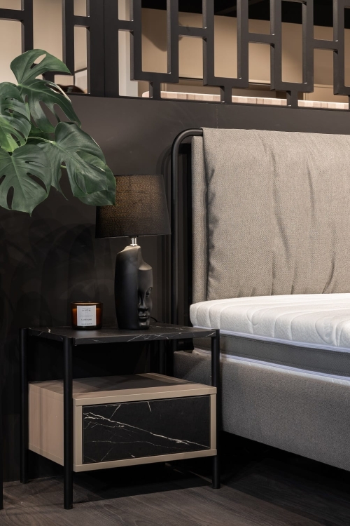 Nowoczesne łóżko na metalowych nogach z tapicerowanym, miękkim wezgłowiem. Połączenie metalu i tkaniny zapewnia elegancję, lekkość i wygodę w sypialni.